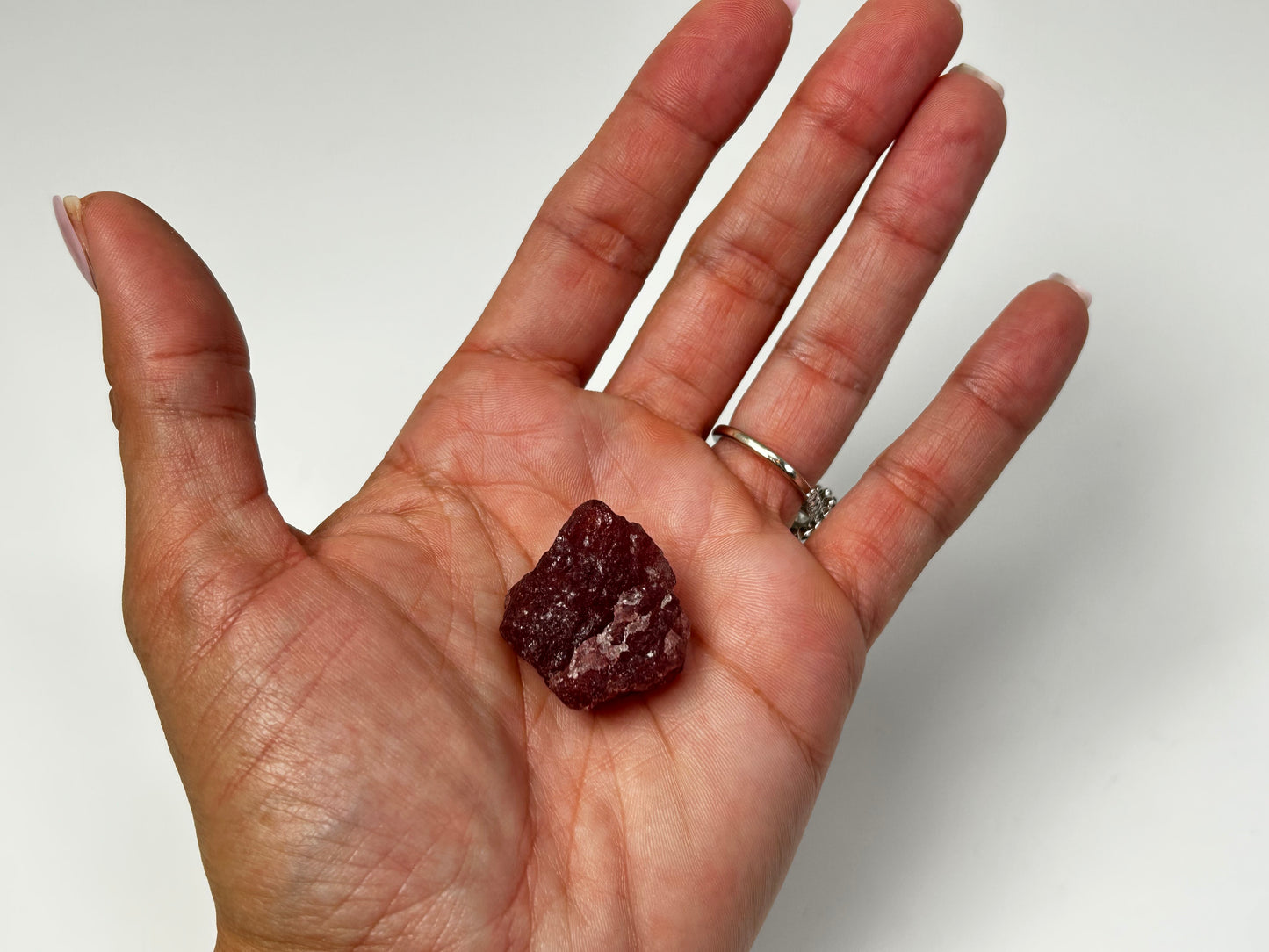 Hand holding a red stone against a white background