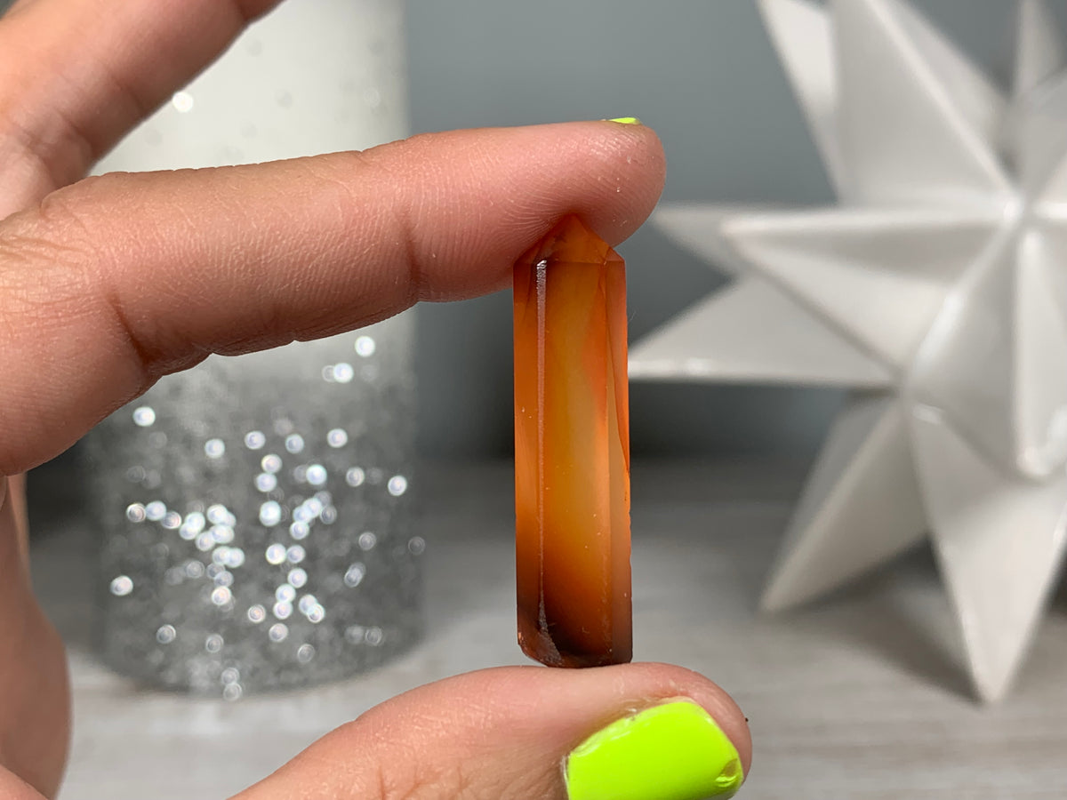 Hand holding Mini Carnelian Crystal Tower for energy and trust on natural background