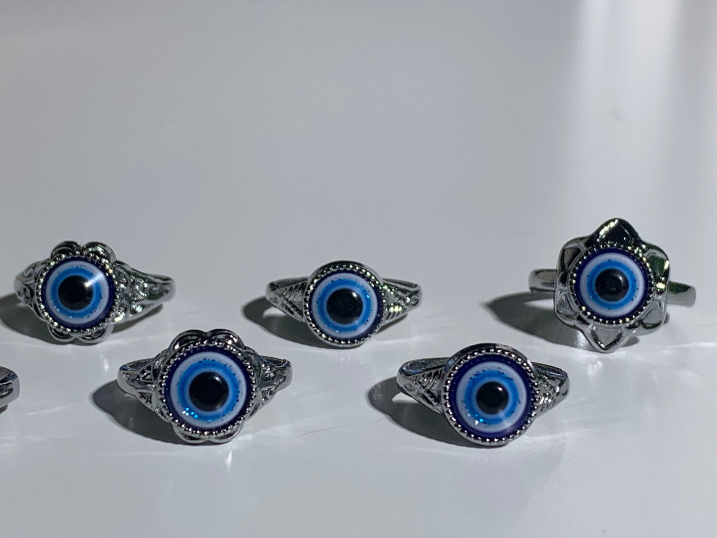 Close-up of Protect Your Peace Silver Evil Eye Rings for energy and trust on a smooth white table