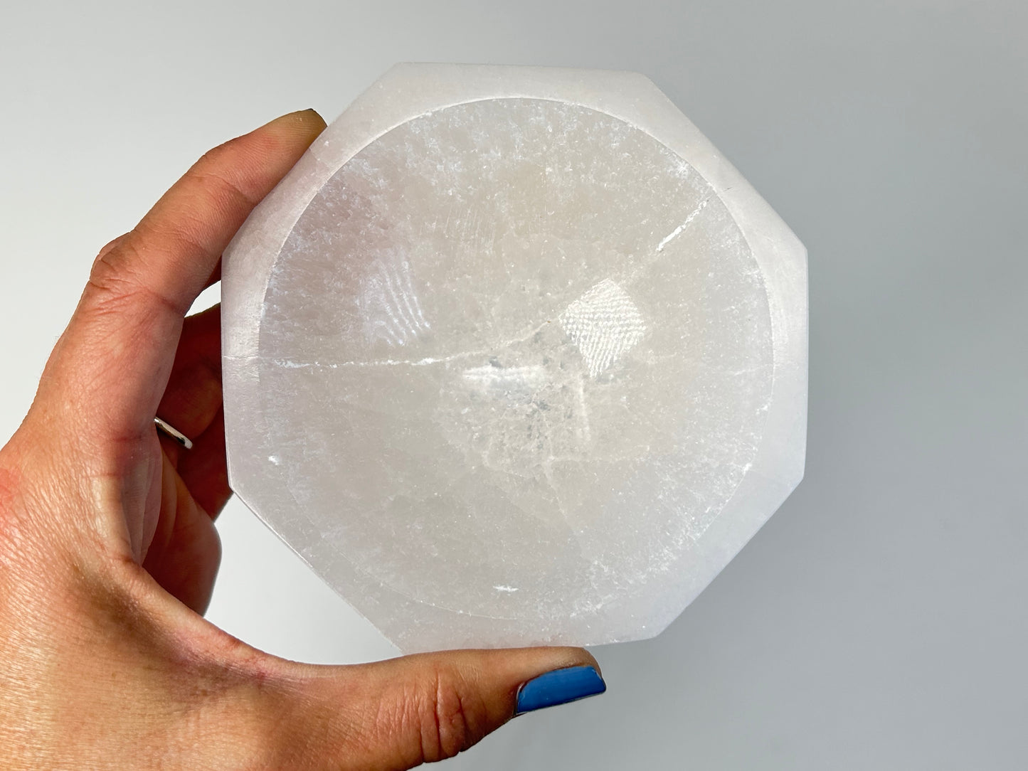 Hand holding a Octagon Selenite Bowl from Morocco for meditation and energy work with white background