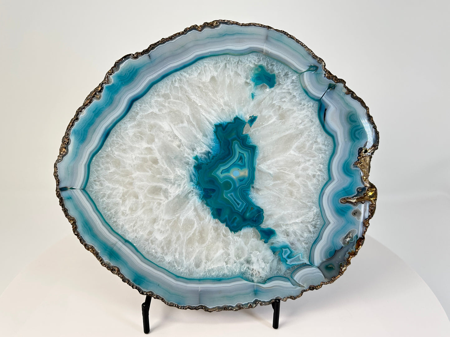 Aqua Blue Agate Geode Slice with gold trim for natural grounding on table with white background 