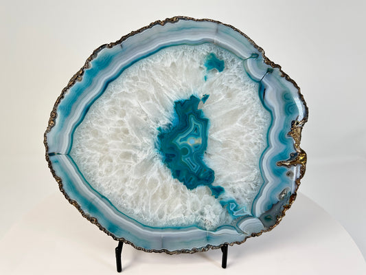 Aqua Blue Agate Geode Slice with gold trim for natural grounding on table with white background 