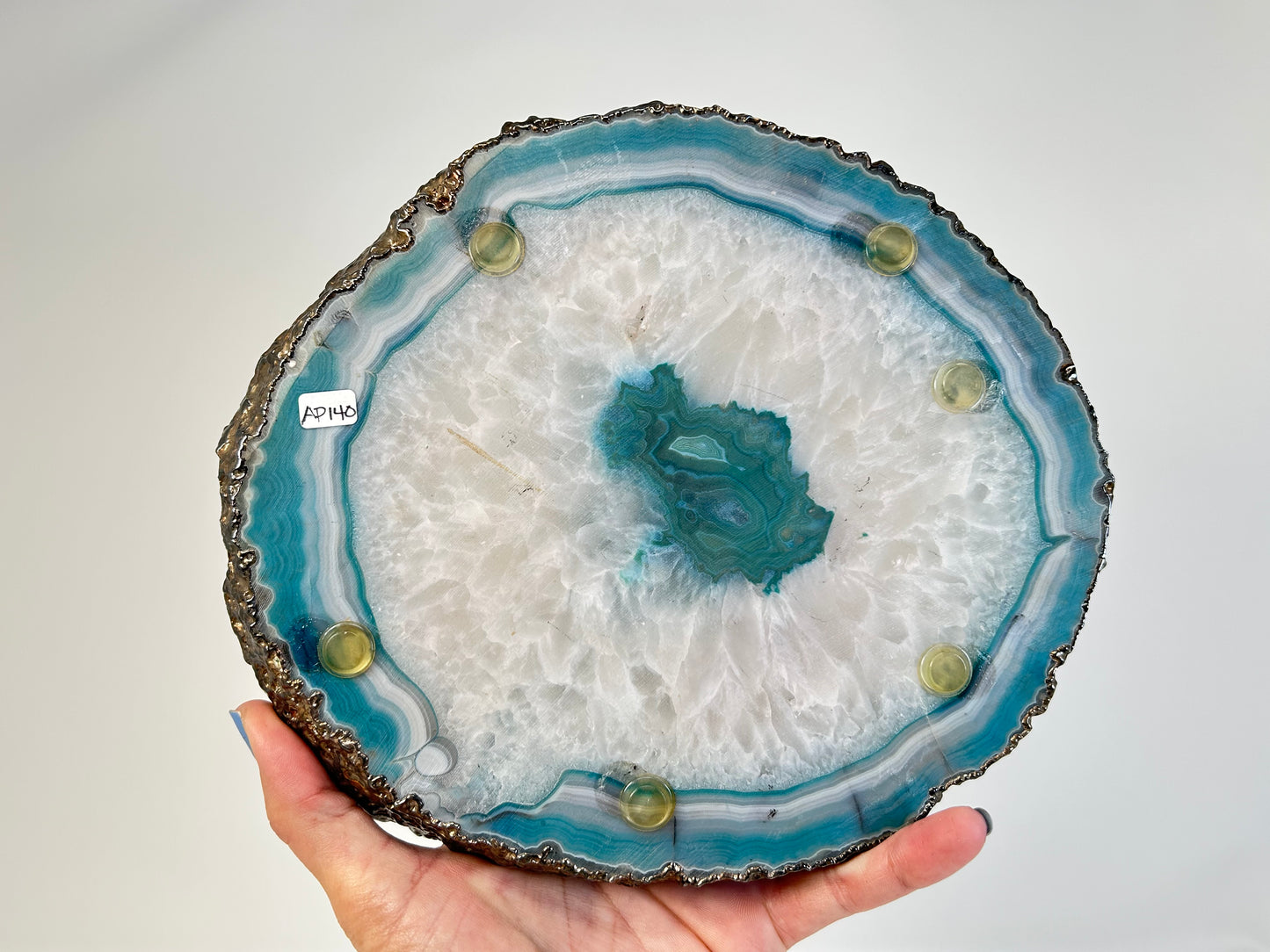 Geode slice with blue and white interior held by a hand against a plain background