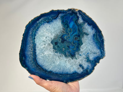 Hand holding Blue Agate Stone Plate with gold trim ethically sourced gemstone crystal spiritual healing