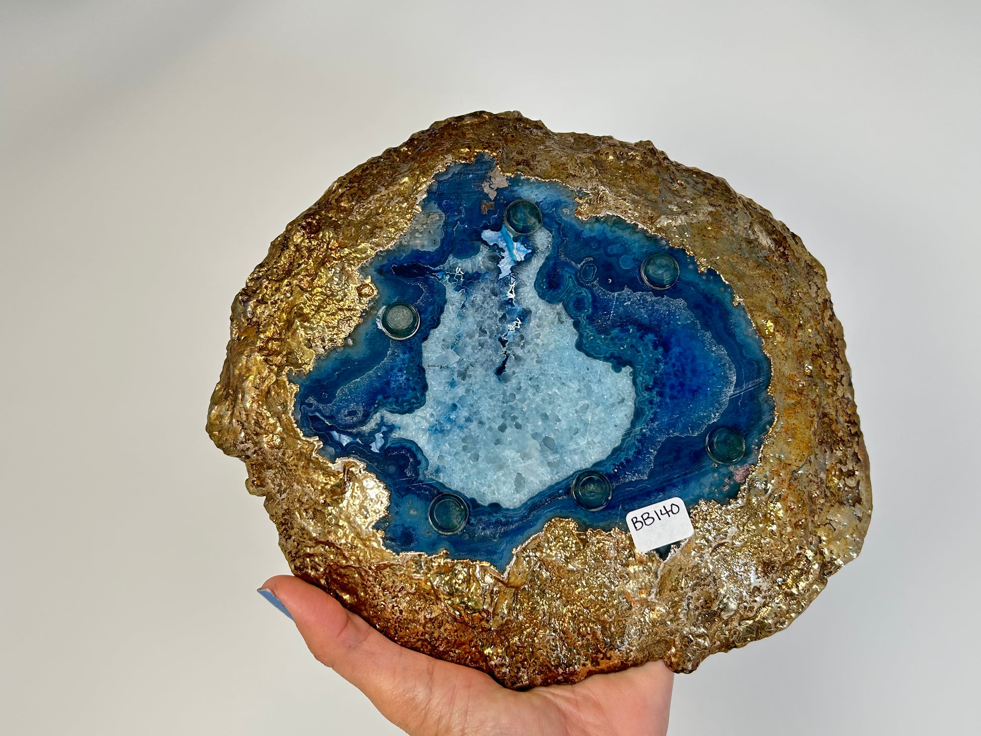 Hand holding a Blue Agate Stone Plate with gold trim for meditation and energy work with white background