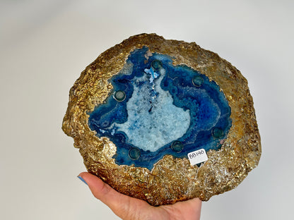 Hand holding a Blue Agate Stone Plate with gold trim for meditation and energy work with white background