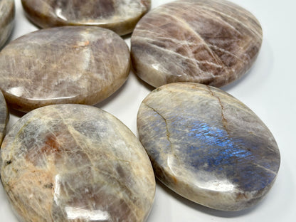 Round Blue Moonstone with Sunstone Palm Stones on a white background