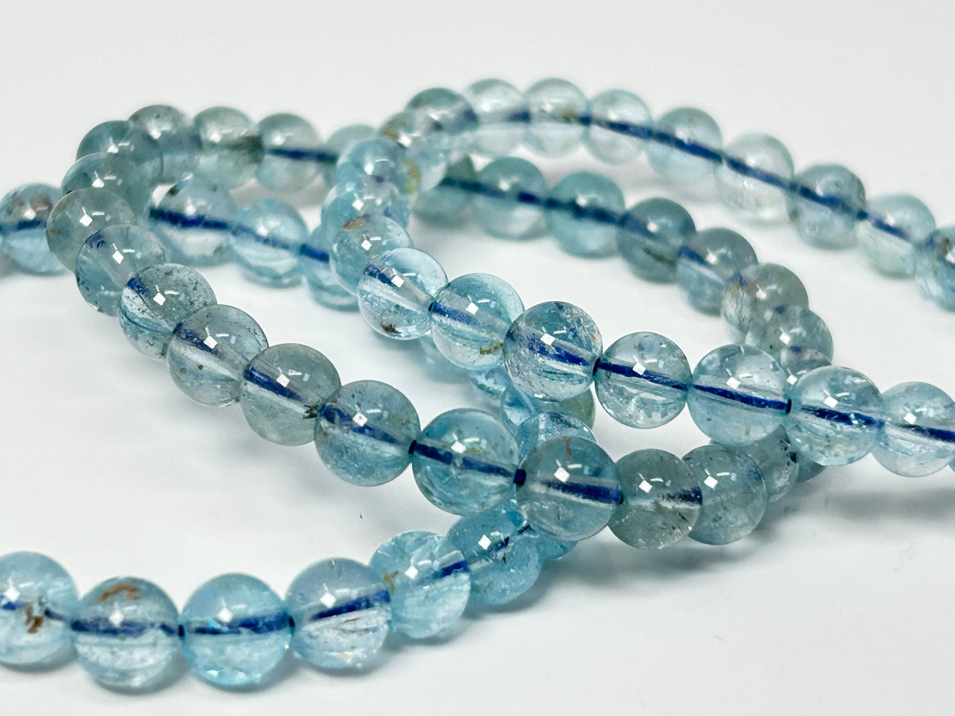 String of light Blue Topaz Bracelet beads for meditation mindfulness and grounding with a white background