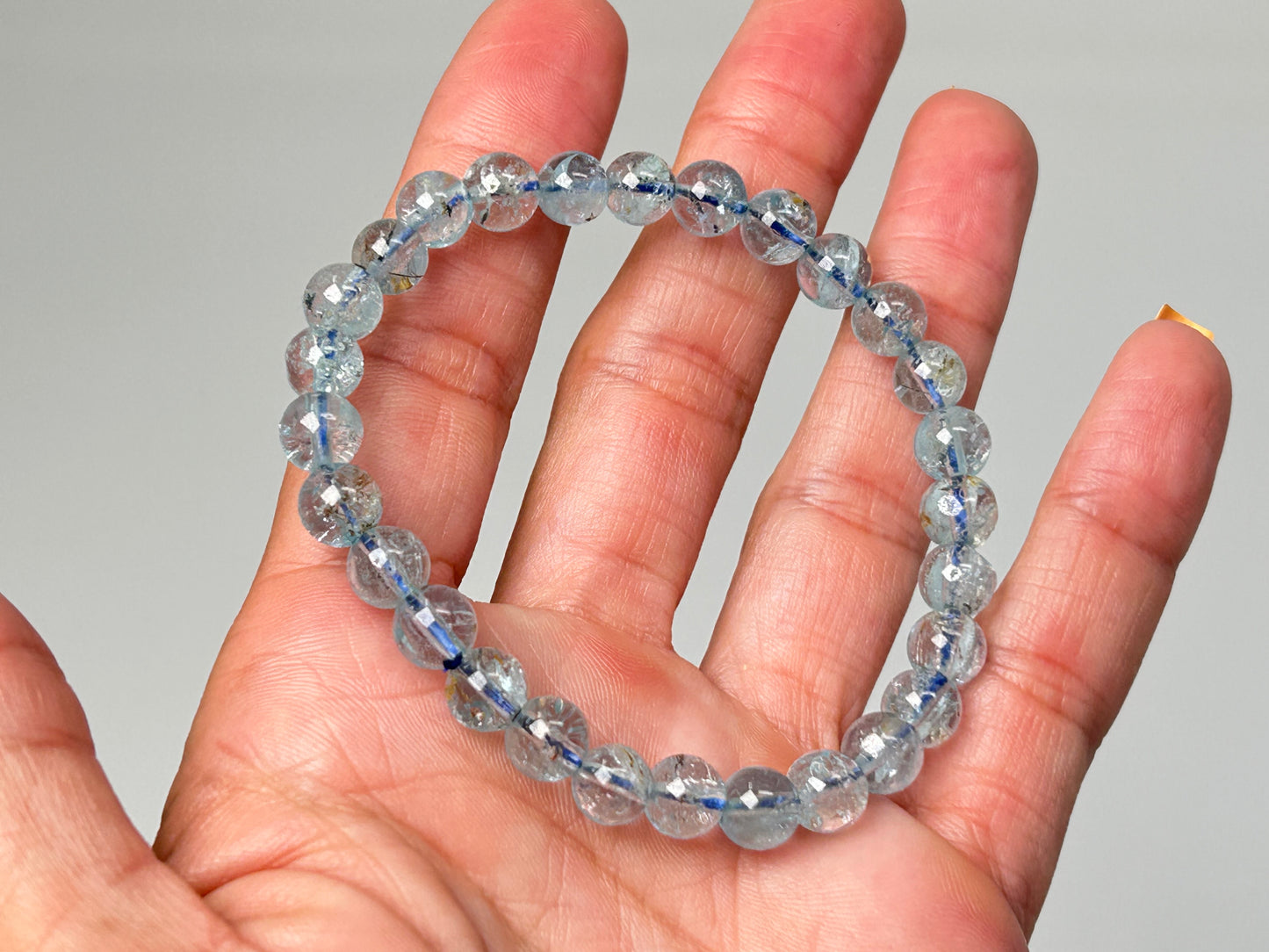 Blue Topaz Bracelet for meditation mindfulness and grounding on a hand against a gray background