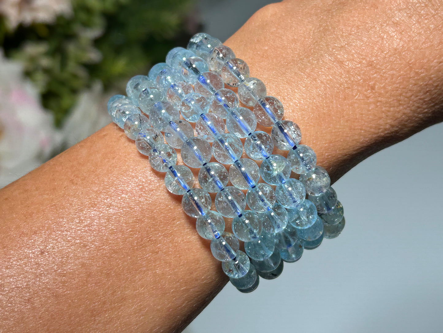 Blue Topaz Bracelet for meditation mindfulness and grounding on a wrist with a blurred floral background