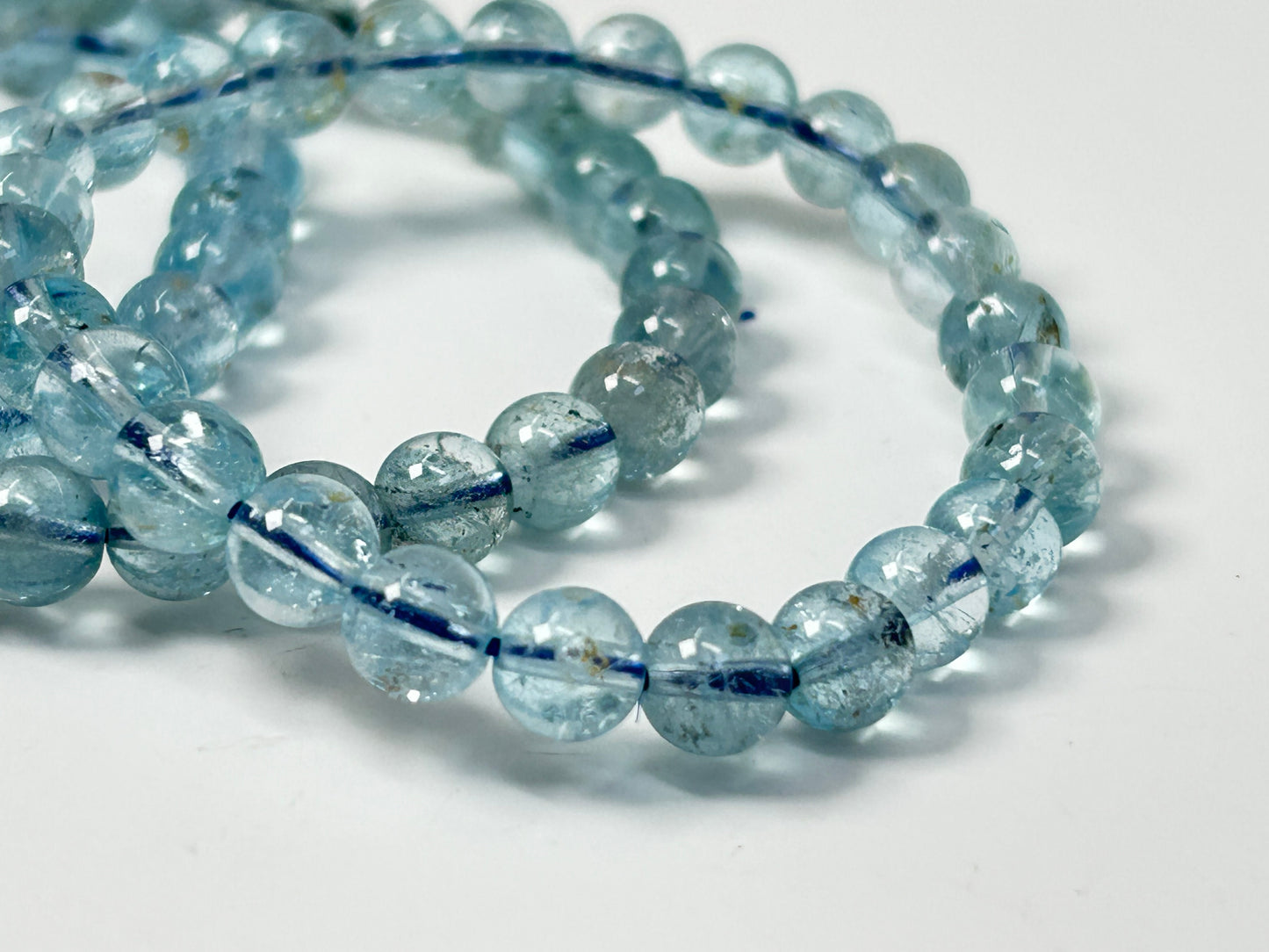 Close-up of a string of Blue Topaz Bracelet beads for meditation mindfulness and grounding on a white background