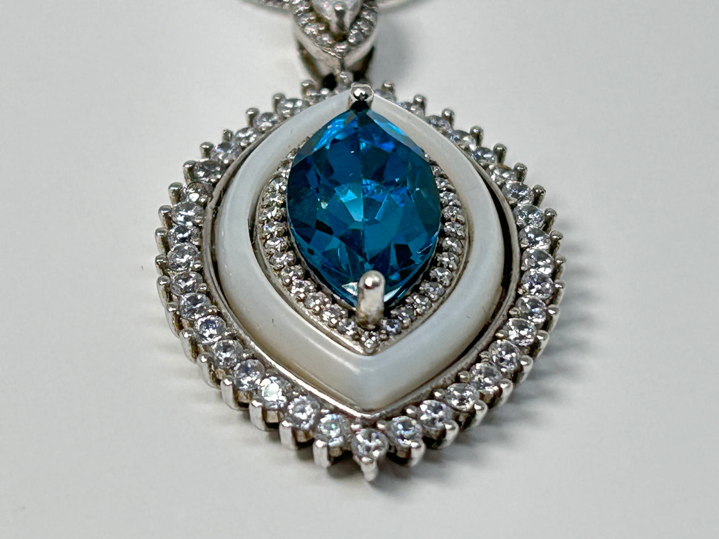 Blue Topaz Eye Pendant with Cubic Zirconia in Sterling Silver on table with white background.