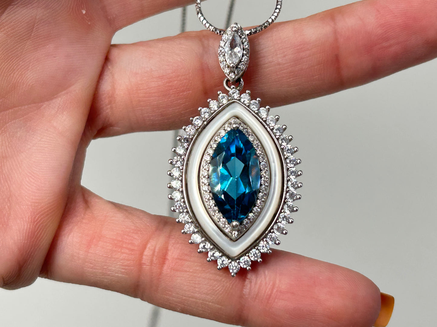 Close up of a Blue Topaz Eye Pendant with Cubic Zirconia in Sterling Silver for meditation and energy work with white gray background