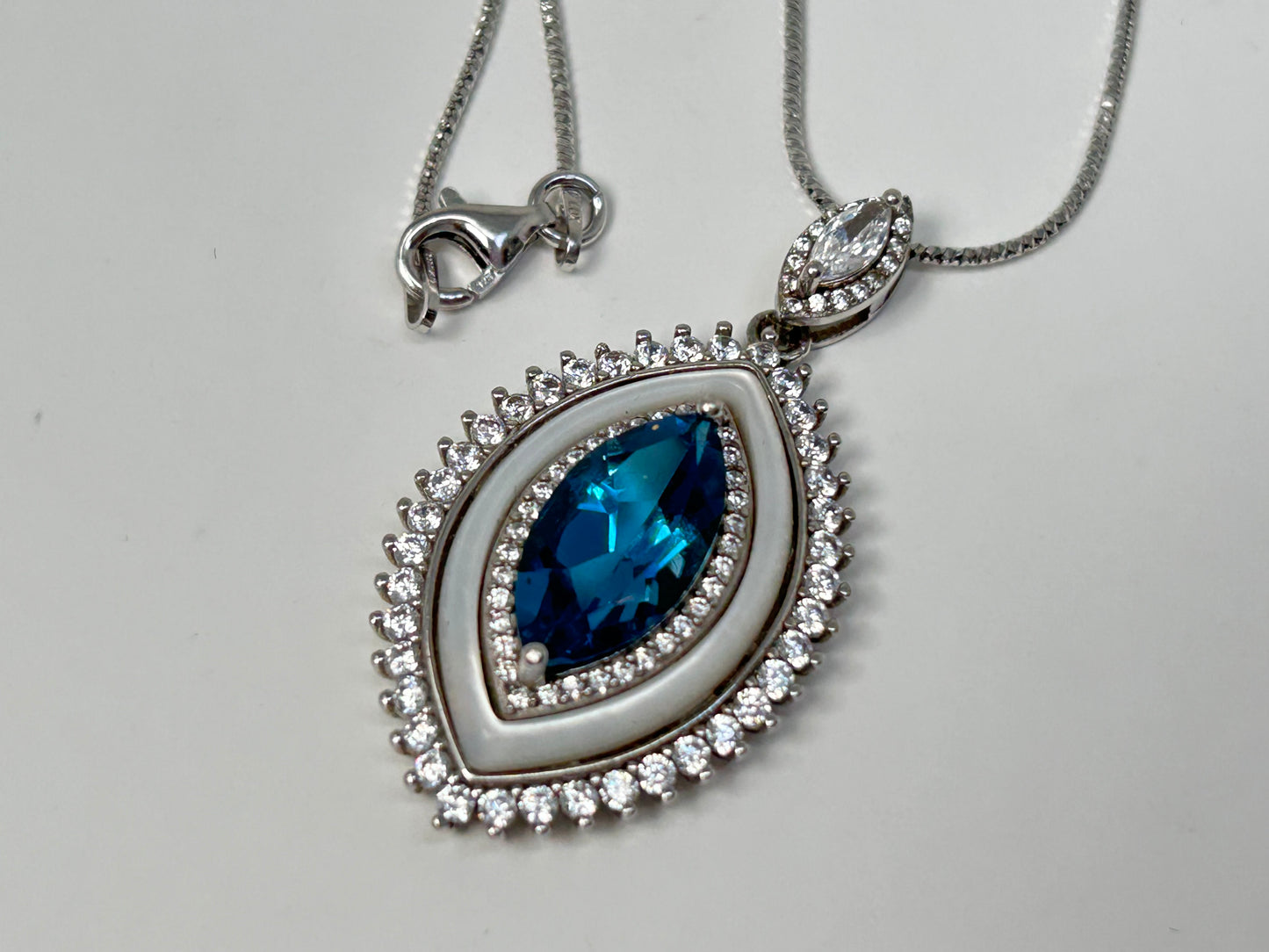 Silver necklace with a Blue Topaz Eye Pendant with Cubic Zirconia in Sterling Silver on a light gray background