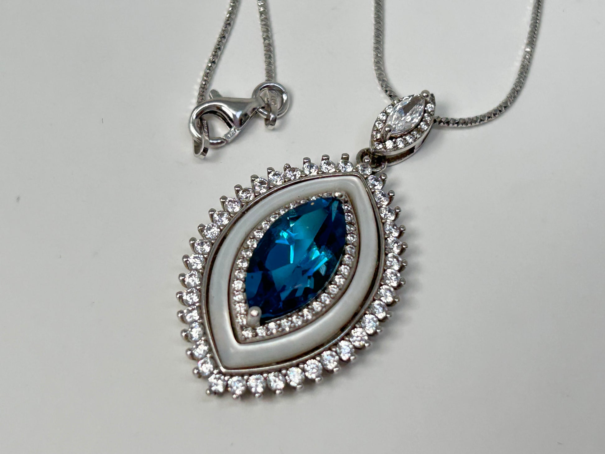 Silver necklace with a Blue Topaz Eye Pendant with Cubic Zirconia in Sterling Silver on a light gray background