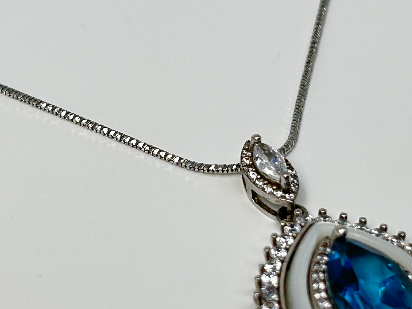 Close up of a Blue Topaz Eye Pendant with Cubic Zirconia in Sterling Silver for aura cleansing gemstone reiki energized with white gray background