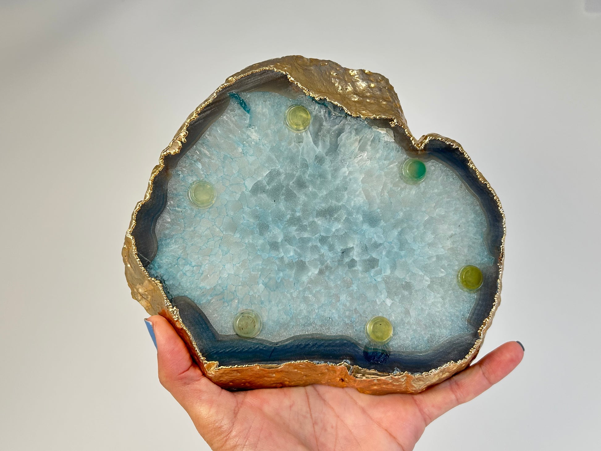 Hand holding an ethically sourced Calming and harmonizing Dyed Blue Agate Plate for meditation over white background
