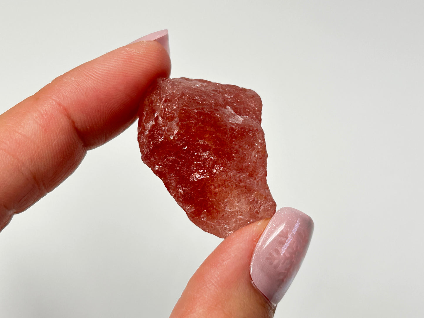 Hand holding Cherry Tanzurine Quartz for meditation and energy work with white background.