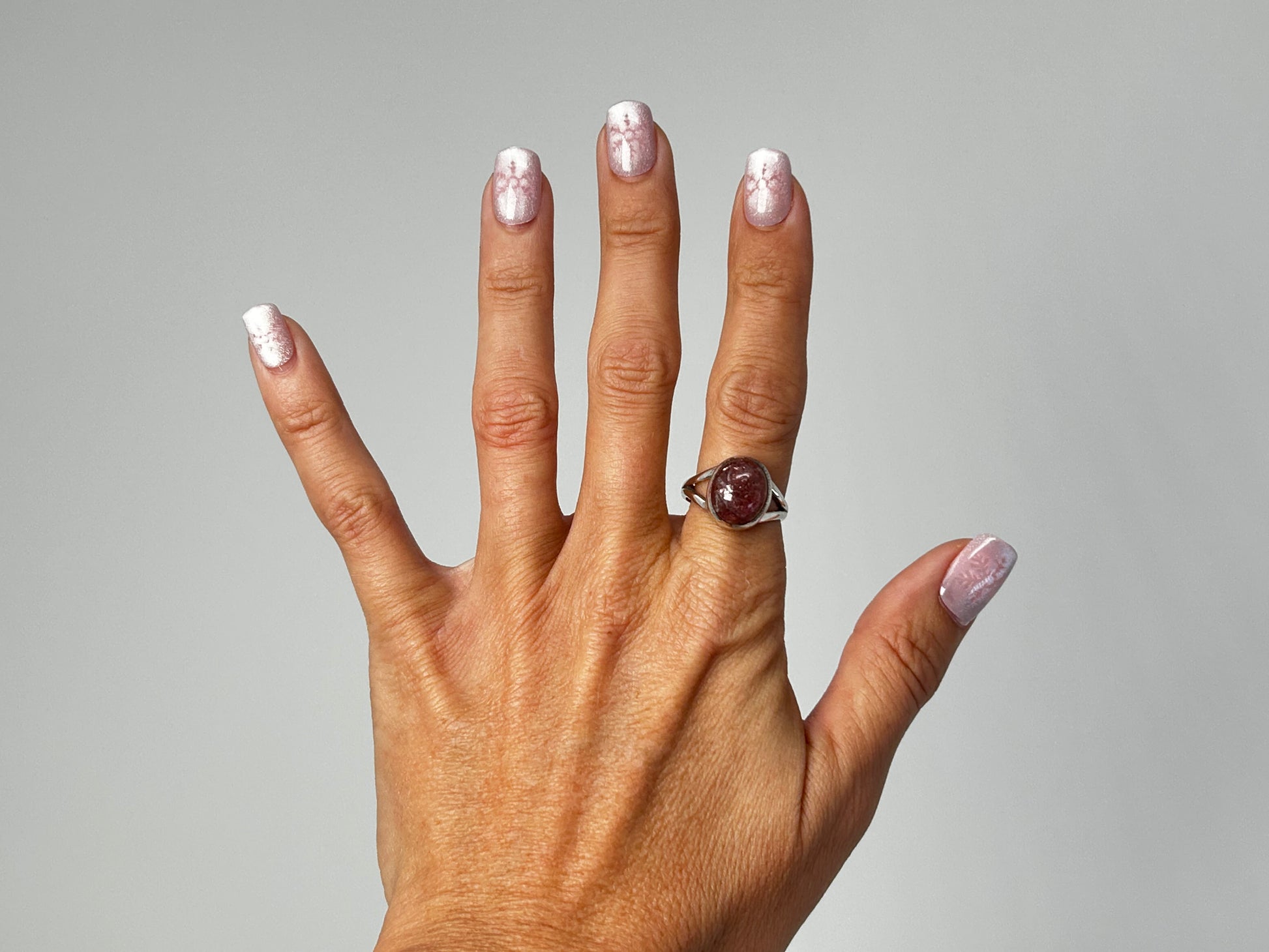 Hand wearing a Cherry Tanzurine Sterling Silver Ring for meditation and energy work with white background.