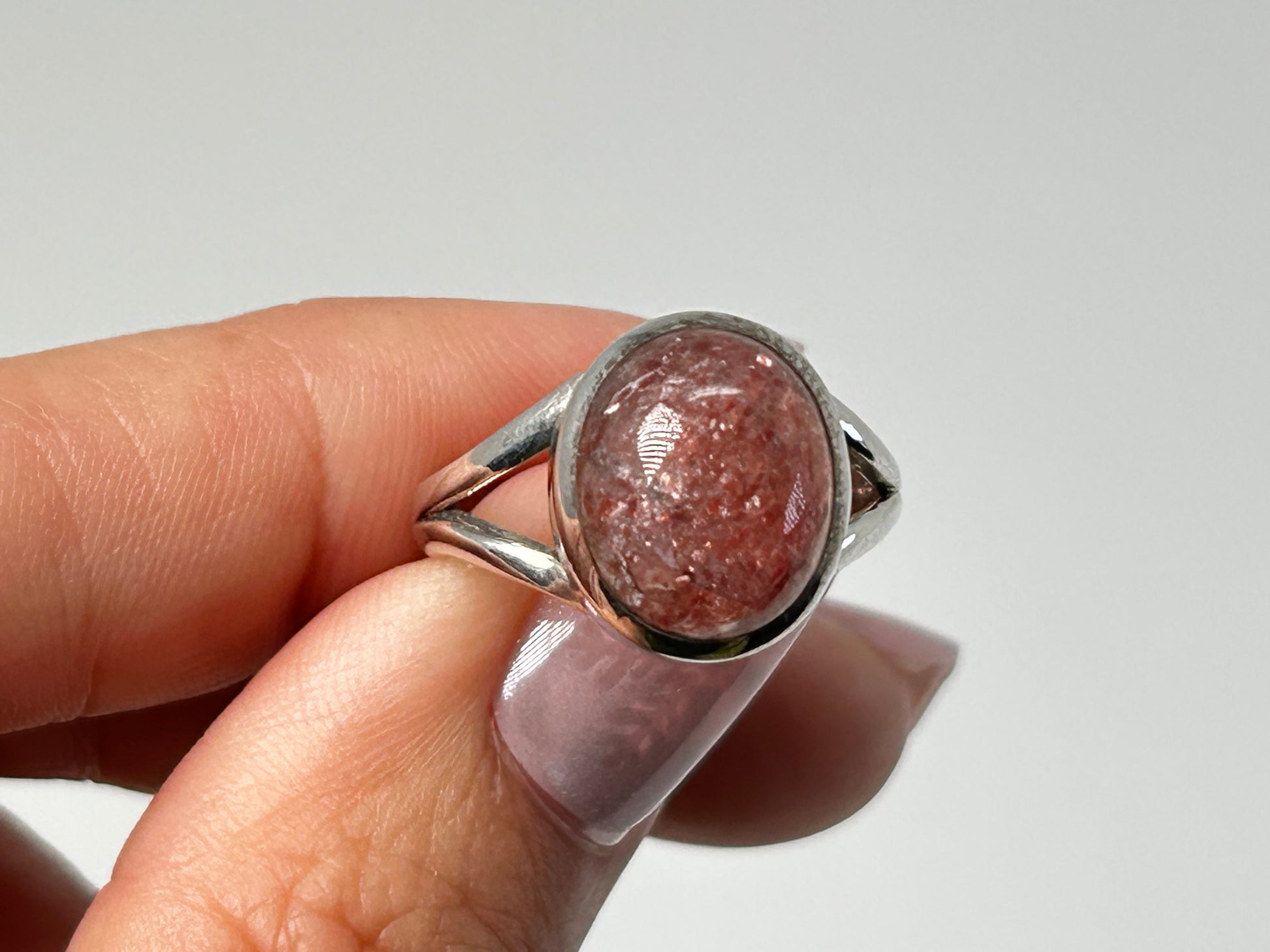 Hand holding Cherry Tanzurine Sterling Silver Ring on table top with white background