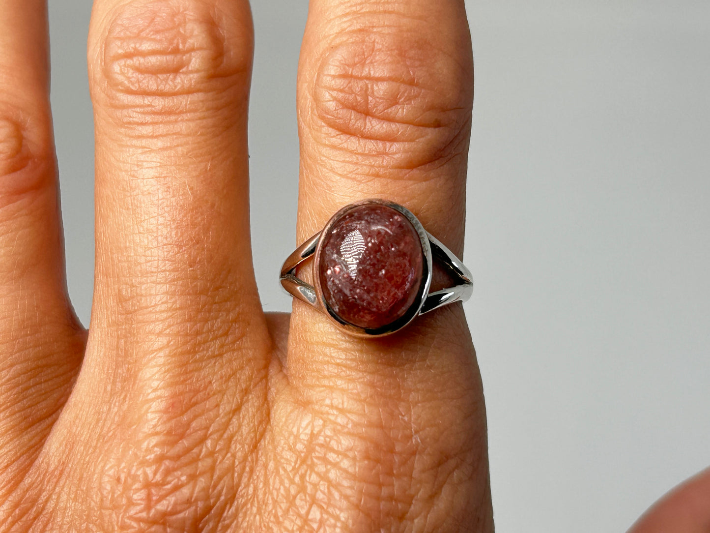 Hand wearing ethically sourced Cherry Tanzurine Sterling Silver Ring for meditation over white background.