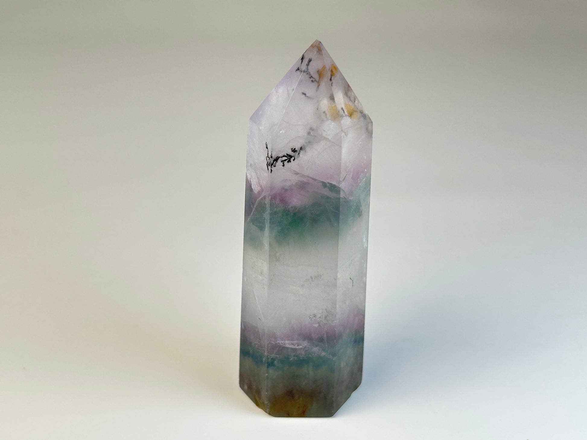 Dendritic Fluorite Tower gemstone on table with white background. 

