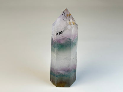 Dendritic Fluorite Tower gemstone on table with white background. 
