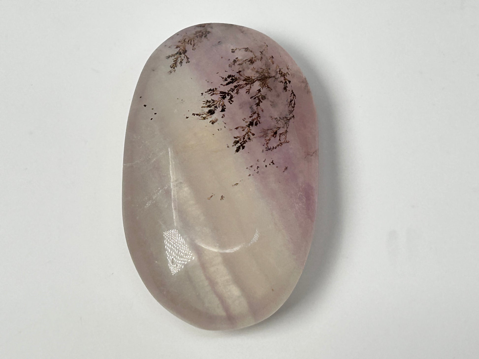 Oval-shaped Dendritic Fluorite in table with purple and white hues on a white background