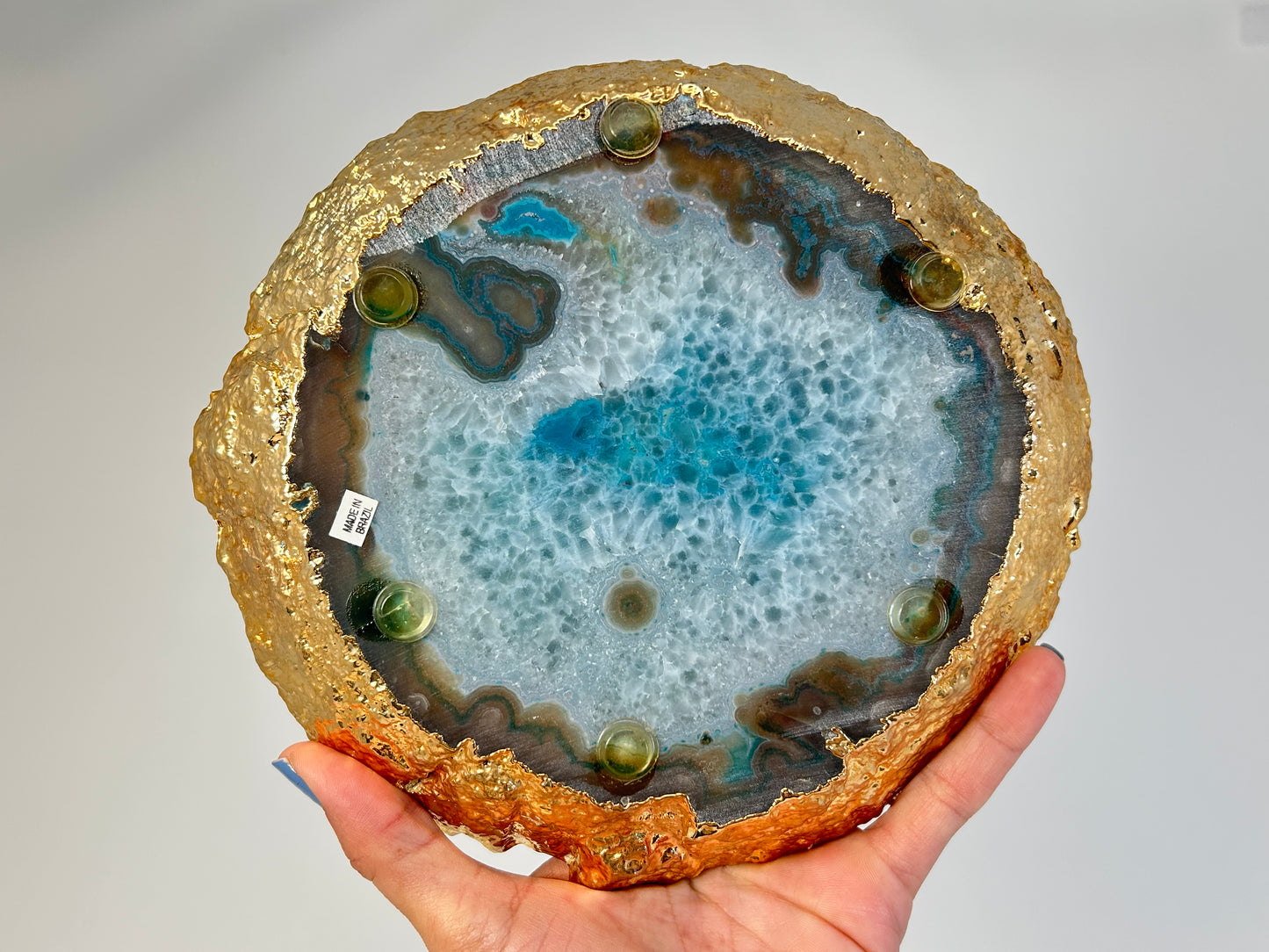 Dyed Blue Agate Plate with gold trim held in a hand against a gray background
