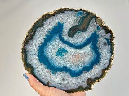 Dyed Blue Agate Plate with gold trim held by a hand against a neutral background