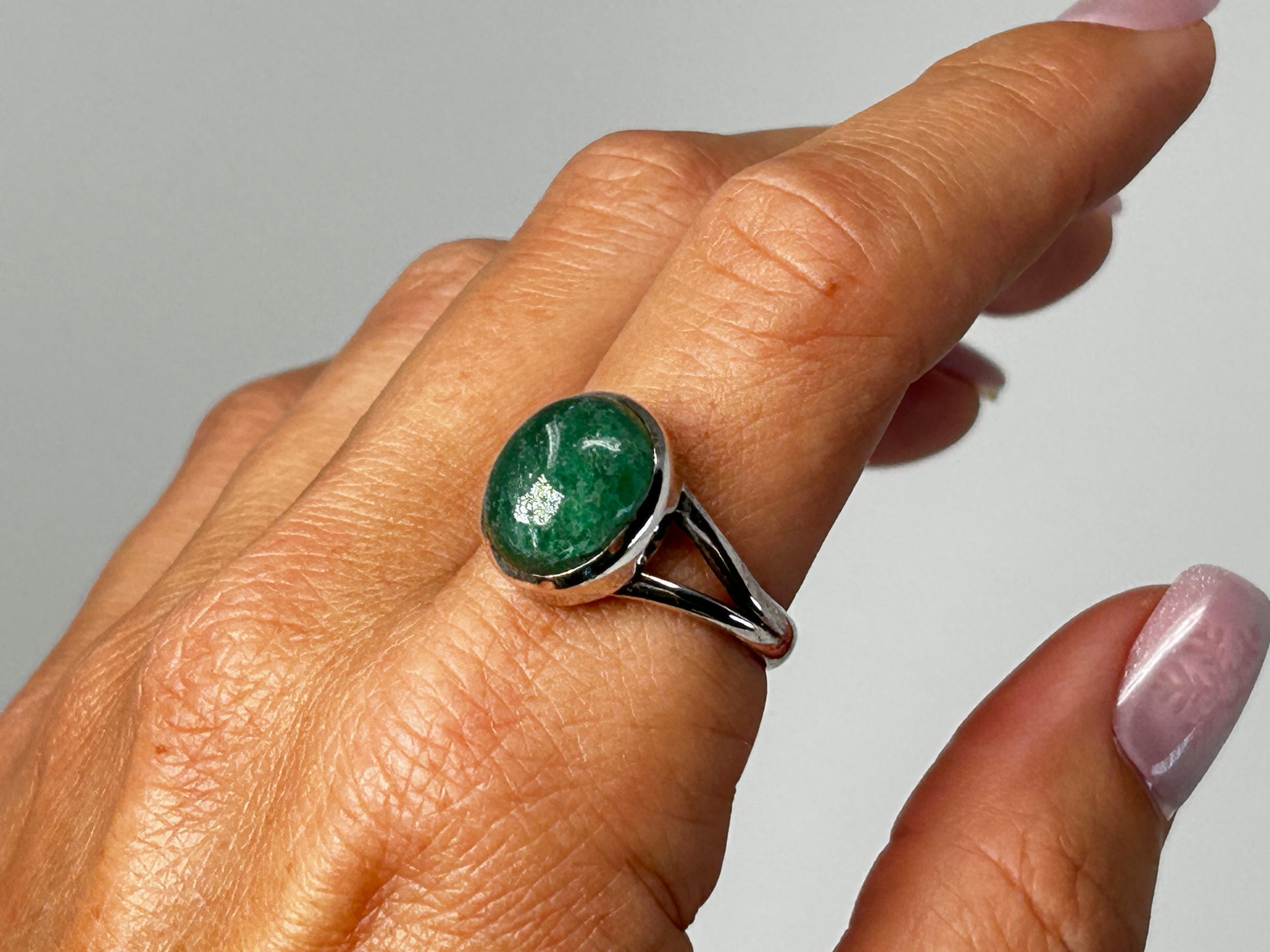 Hand wearing an Emerald Tanzurine Sterling Silver Ring for meditation and energy work with white background.