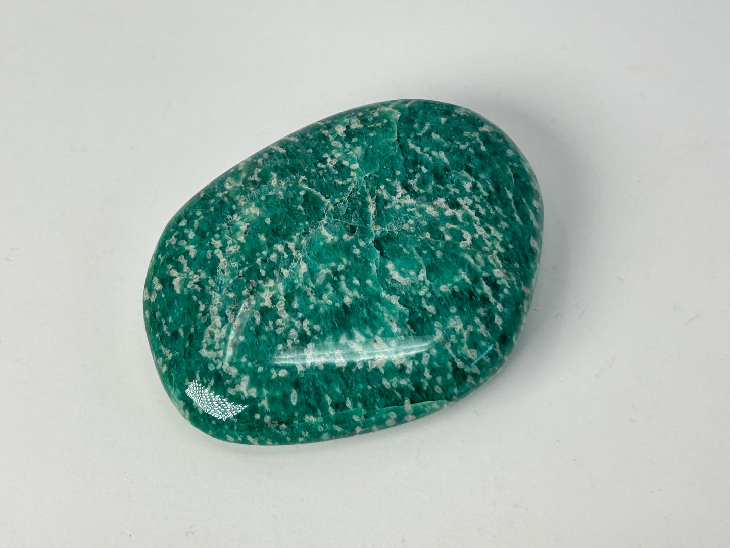 Speckled Energized Emerald Green Amazonite Palm Stone on a gray background