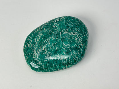 Speckled Energized Emerald Green Amazonite Palm Stone on a gray background