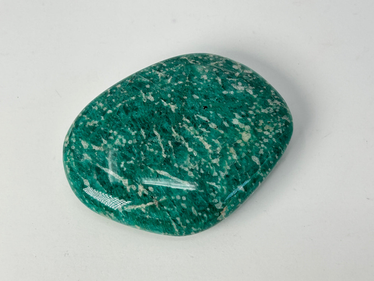 Speckled Energized Emerald Green Amazonite Palm Stone on a gray background