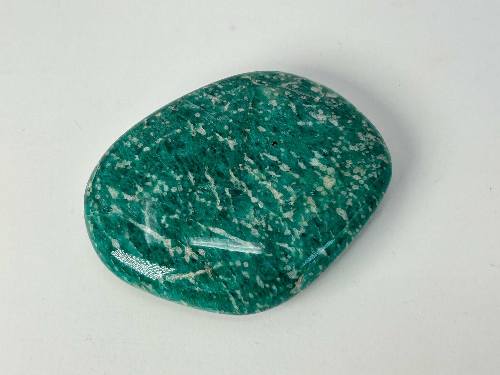 Speckled Energized Emerald Green Amazonite Palm Stone on a gray background