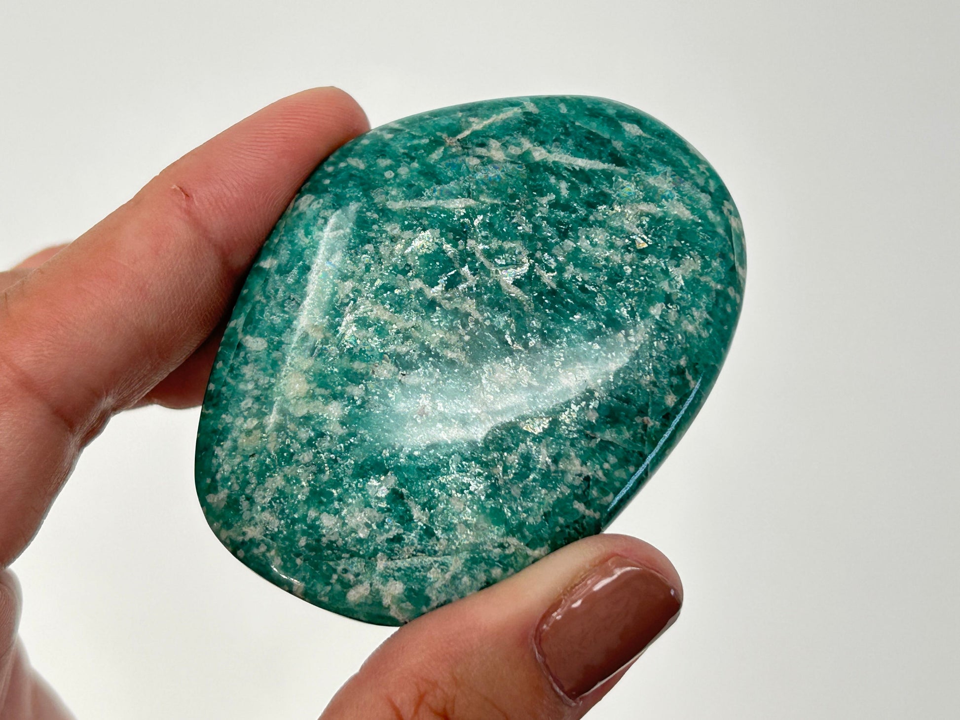 Hand holding a Energized Emerald Green Amazonite Palm Stone  against a white background