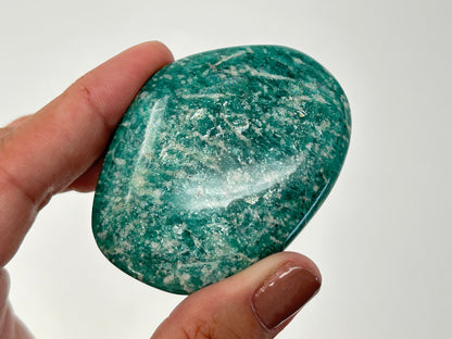 Hand holding a Energized Emerald Green Amazonite Palm Stone  against a white background
