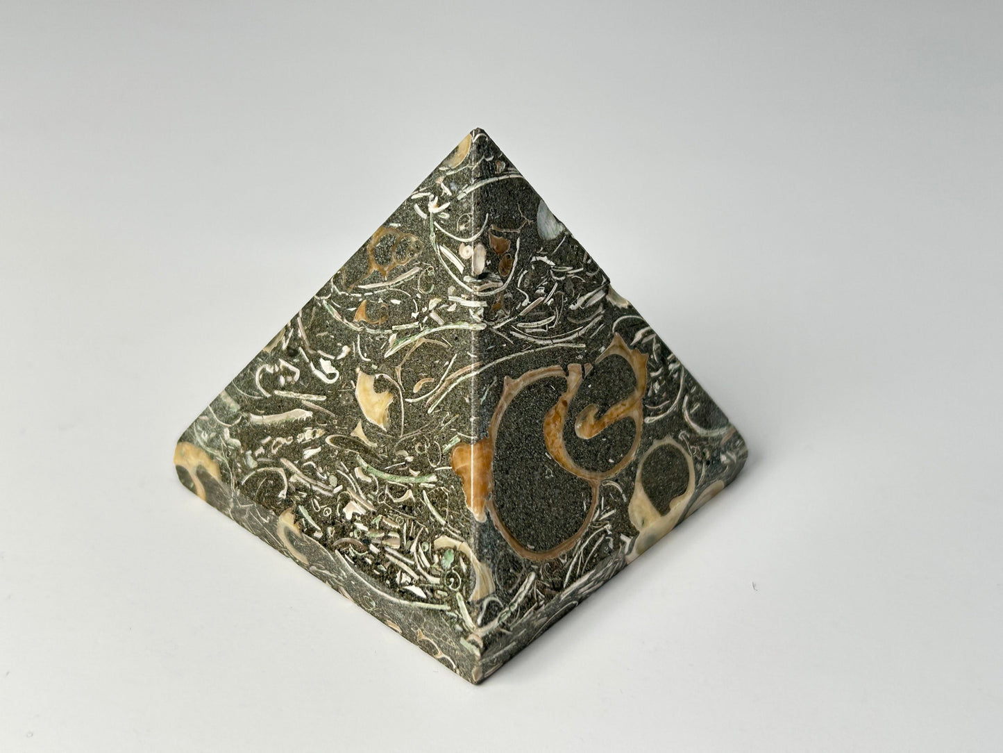 Decorative Grounding Turritella Agate Pyramid with intricate patterns on a gray background