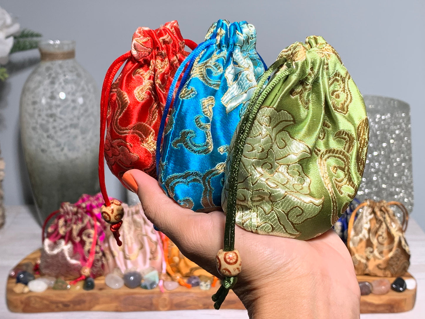 Hand holding Kids Mystery Crystal Bag-Childhood Memories Collection bags for natural grounding with bamboo and flower background