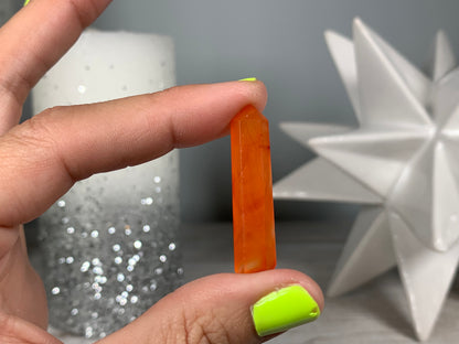 Hand holding Mini Carnelian Crystal Tower for energy and trust on natural background