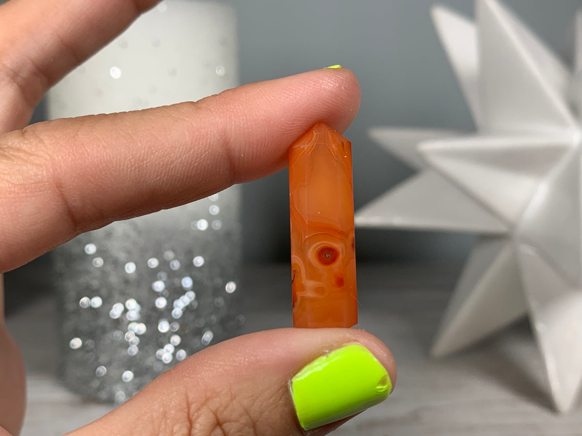 Hand holding Mini Carnelian Crystal Tower for energy and trust on natural background