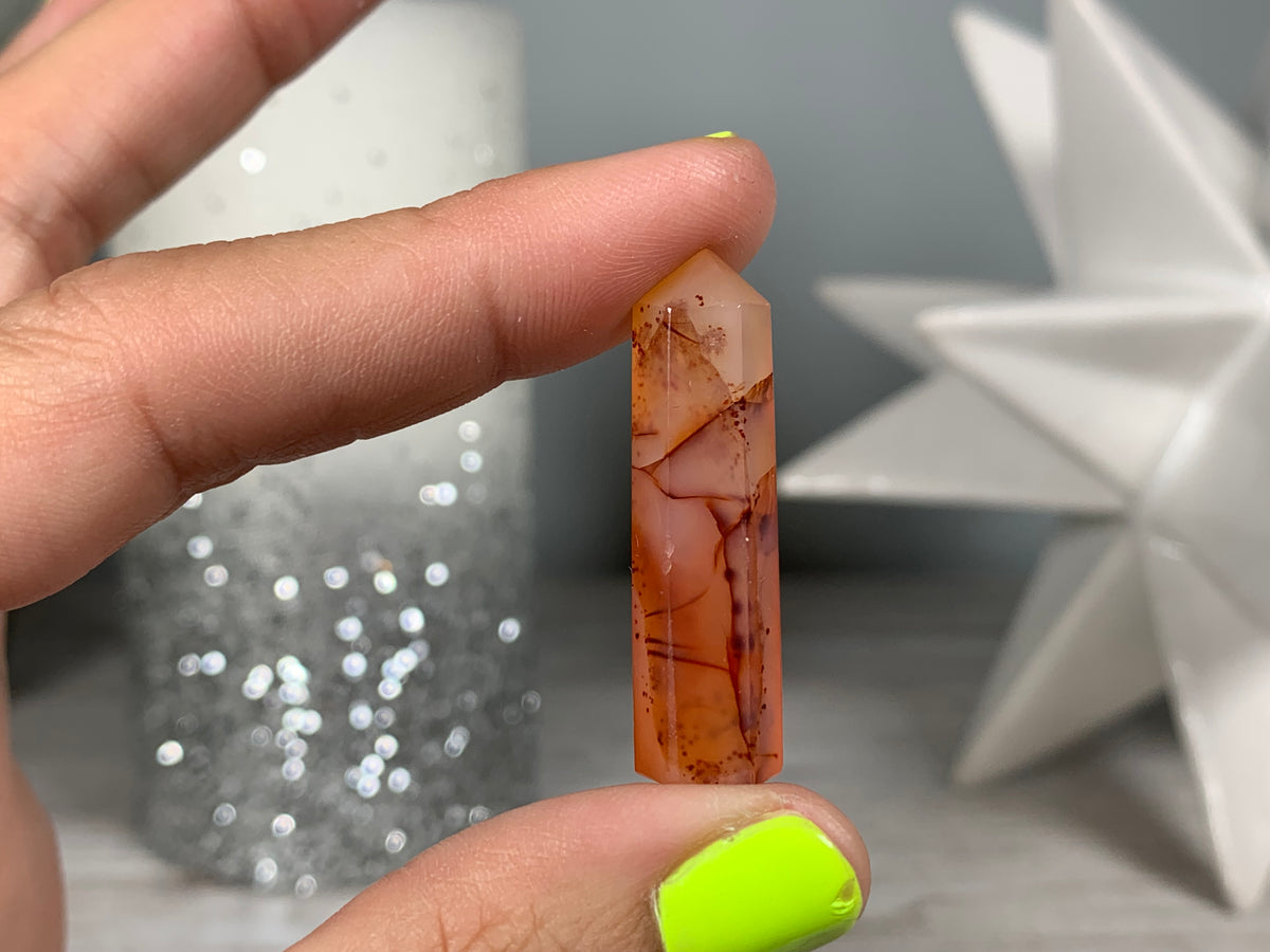 Hand holding Mini Carnelian Crystal Tower for energy and trust on natural background