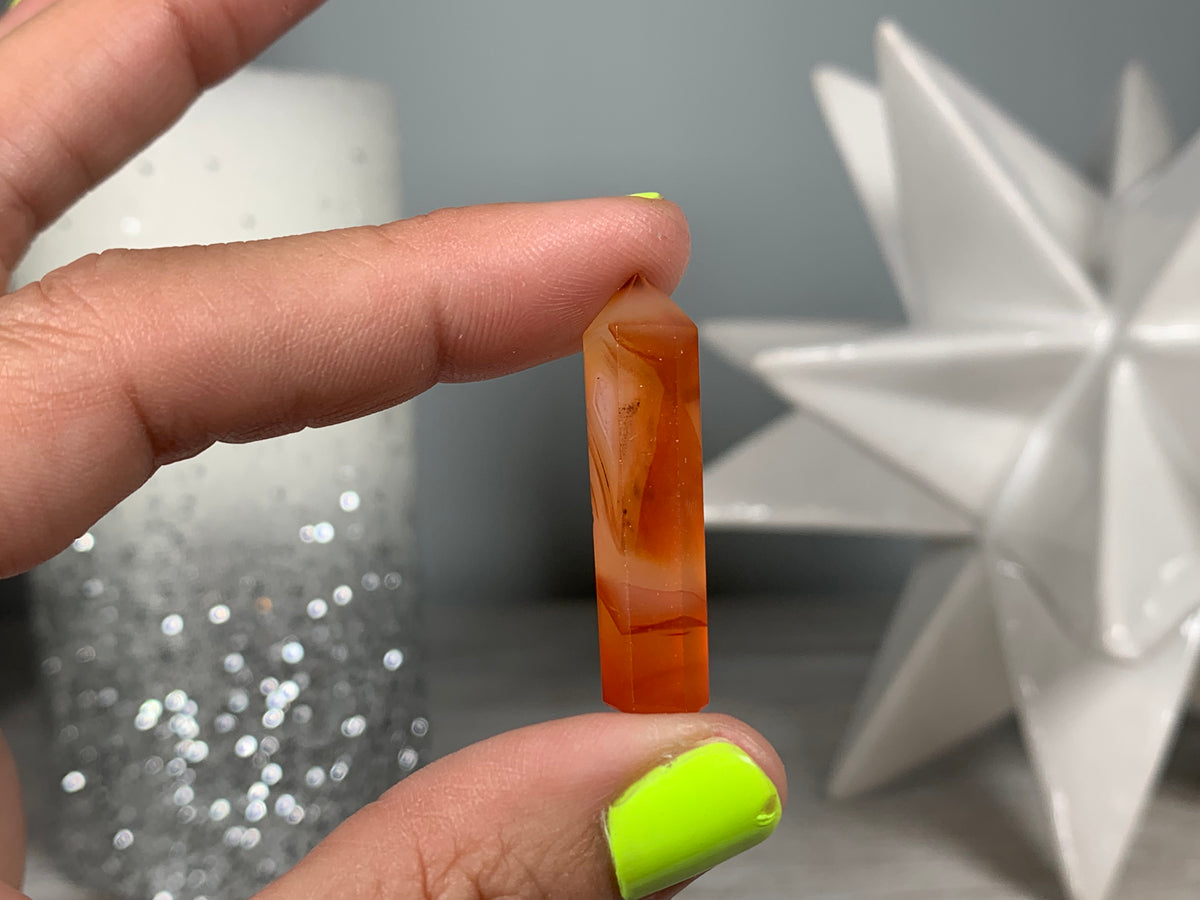 Hand holding Mini Carnelian Crystal Tower for energy and trust on natural background