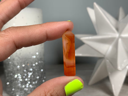 Hand holding Mini Carnelian Crystal Tower for energy and trust on natural background