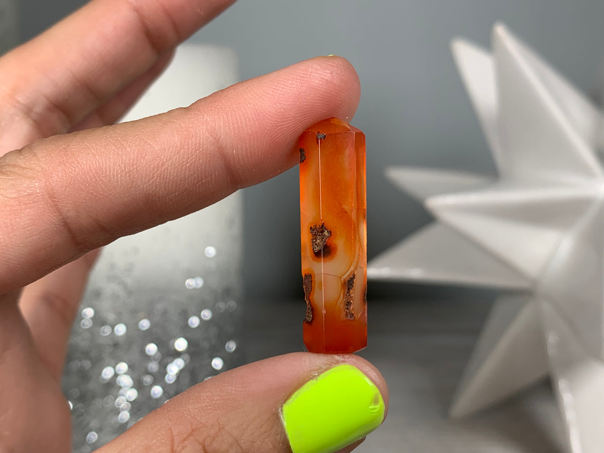 Hand holding Mini Carnelian Crystal Tower for energy and trust on natural background