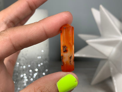 Hand holding Mini Carnelian Crystal Tower for energy and trust on natural background