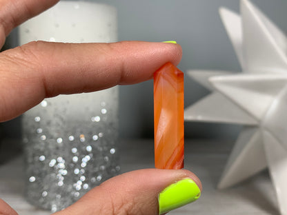 Hand holding Mini Carnelian Crystal Tower for energy and trust on natural background