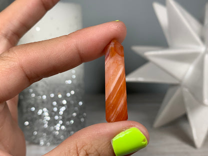 Hand holding Mini Carnelian Crystal Tower for energy and trust on natural background