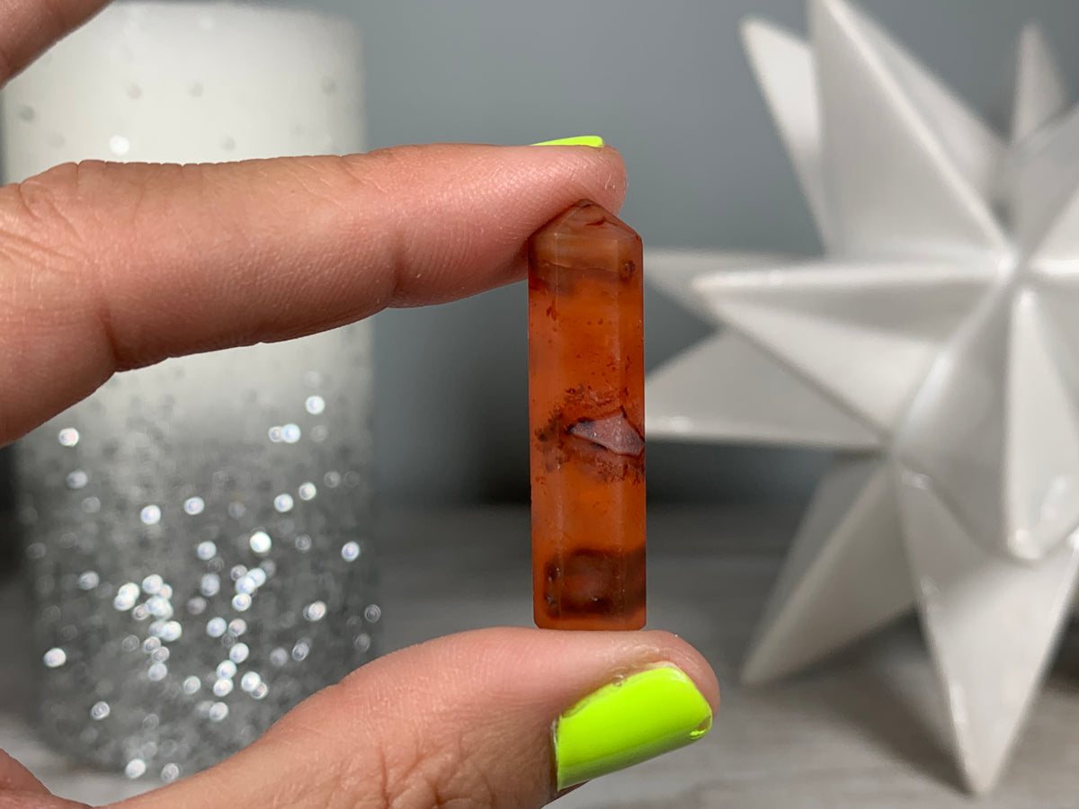 Hand holding Mini Carnelian Crystal Tower for energy and trust on natural background