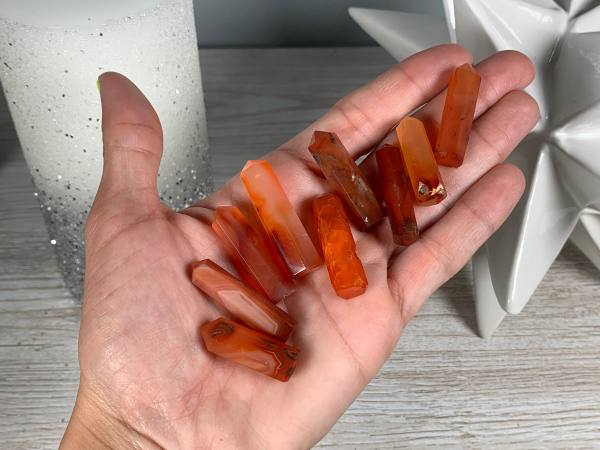 Hand holding Mini Carnelian Crystal Tower for energy and trust on natural background